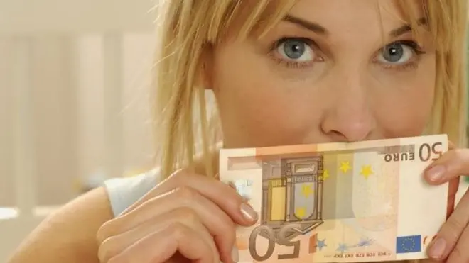 فتاة تمسك بورقة نقدية