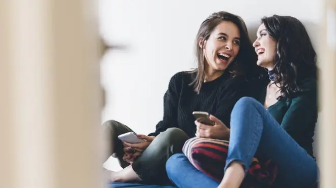 Young people laughing sitting on a bed