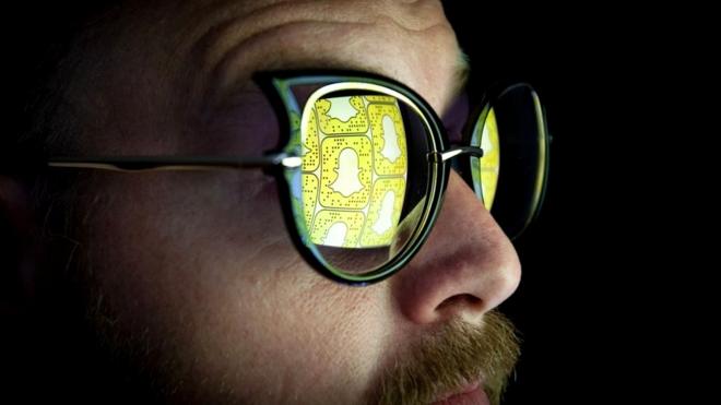 Hombre con bigote y gafas de sol en las que se refleja el logo de Snapchat