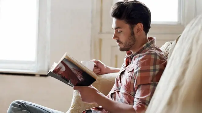 شاب يجلس منفردا ويقرأ في كتاب