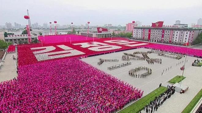 Pyongyang's main square, a sea of pink and red being waved by hundreds of thousands of people standing in fixed positions, to spell out slogans in Korean