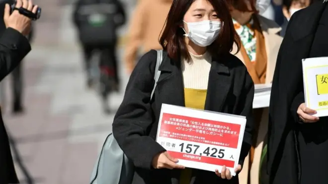 تقول موموكو نوجو، التي تظهر في الصورة وهي تحمل العريضة التي شاركت في إطلاقها، إنه كان من المهم الحديث بصراحة ووضوح عن تصريحات موري