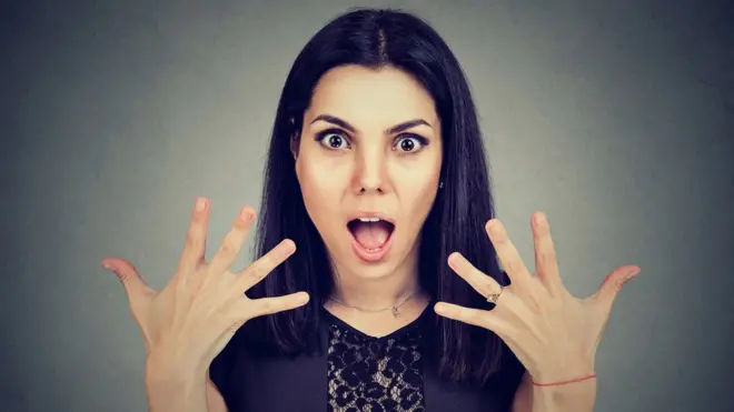Mujer con cara de sorpresa mostrando las uñas.