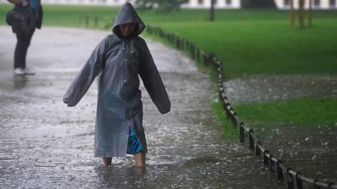 woman wading through floodwater in London