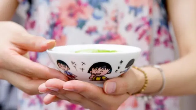 Một người tham gia cầm một chiếc chén cô đã sử dụng từ thời thơ ấu. Hình vẽ hoài cổ trên chén mang đến cảm giác luyến tiếc quá khứ.