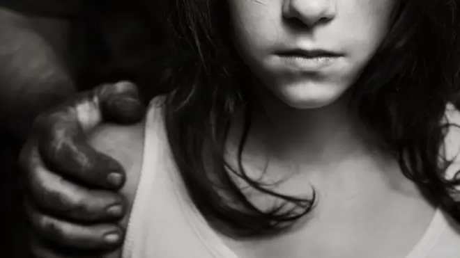 Una niña con unas manos atrás de ella