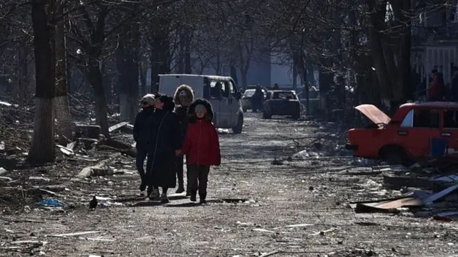 Local residents walk near residential buildings which were damaged during Ukraine-Russia conflict in the besieged southern port city of Mariupol, Ukraine March 18, 2022
