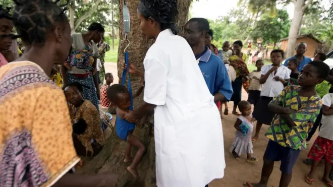 Un enfant qui se fait peser par un personnel de la santé au Kasaï