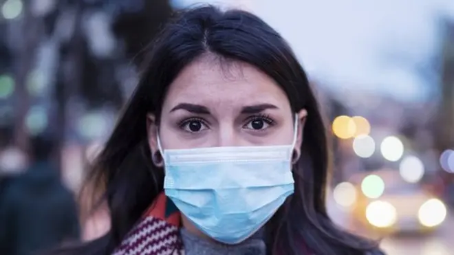 ముఖానికి మాస్క్ వేసుకున్న యువతి