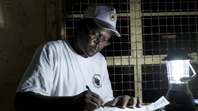 Afisa wa uchaguzi Tanzania akijaza fomu za uchaguzi kwa kutumia taa ya umeme Oktoba 25, 2015.