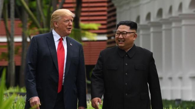 North Korea's leader Kim Jong Un (R) walks with US President Donald Trump (L) during a break in talks at their historic US-North Korea summit