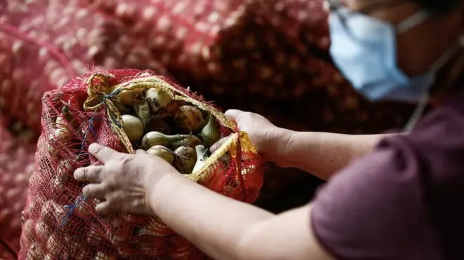 A woman opens a bag of onions in Quezon City, Manila on January 10, 2023
