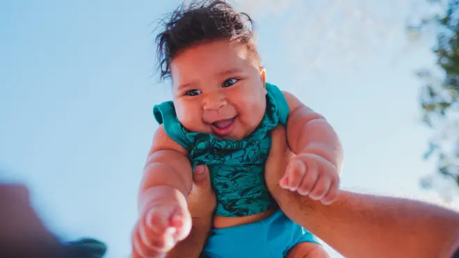 Mãos segurando um bebê no alto