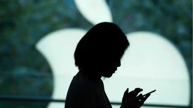 Mulher segura iPhonebonus de 5 aposta ganhafrente ao logo da Apple