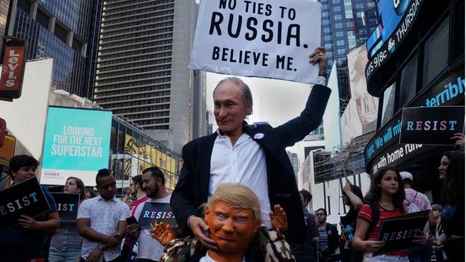 Участник демонстрации в Нью-Йорке с масками Путина и Трампа