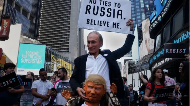 Участник демонстрации в Нью-Йорке с масками Путина и Трампа