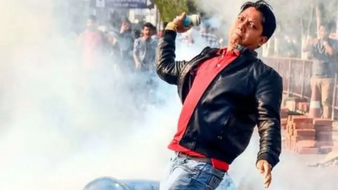 ટિયર ગેસ ફેંકી રહેલા યુવકની તસવીર