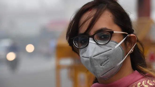 Une femme portant un masque de protection attend le bus public dans des conditions de brouillard à New Delhi le 4 novembre 2019.