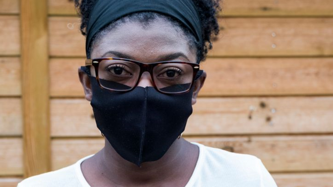 Foto do rosto de uma mulher, que usa uma máscara preta