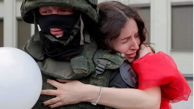 بیلاروس کے دارالحکومت منسک کے آزادی سکوائر میں ایک خاتون سکیورٹی فورسز کے اہلکار سے لپٹی ہوئی ہے۔