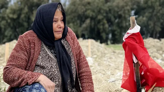 Fethiye Keklik mourns her son next to a Turkish flag