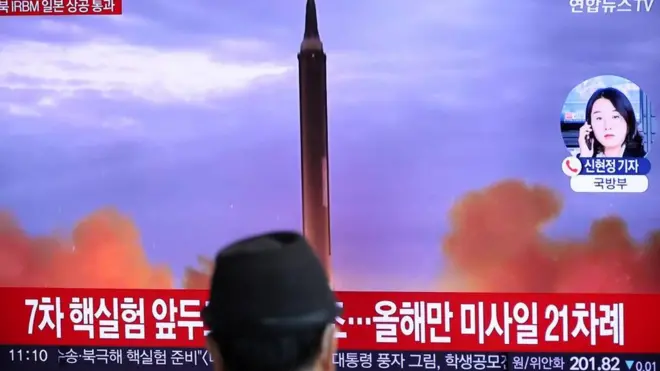 Man in front of public TV screen