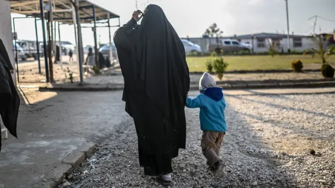 A French woman walks with her child in a camp in northern Syria