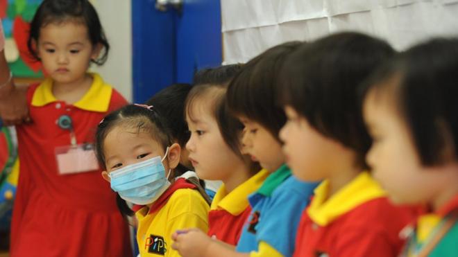 A masked girl sits with classmates at a kindergarten in a residential estate in Hong Kong on June 11, 2009. Hong Kong authorities on June 11 ordered all primary schools in the city to be closed for two weeks after the first cluster of local swine flu cases was found.