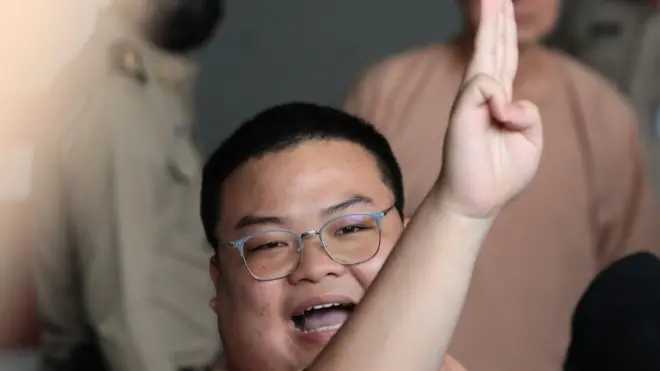 พริษฐ์ ชิวารักษ์ หรือ "เพนกวิน" 1 ใน 22 จำเลยคดีชุมนุม "19 กันยาทวงอำนาจคืนราษฎร" ชูสามนิ้วขณะที่เดินทางจากเรือนจำพิเศษกรุงเทพฯ มาถึงศาลอาญาวันที่ 15 มี.ค.