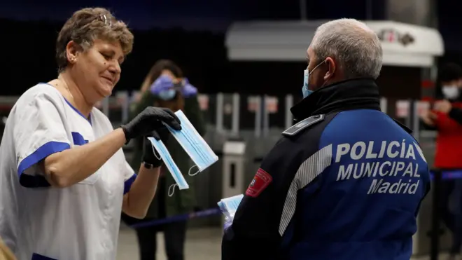 Police officers are handing out face masks at metro and railway stations in Spain