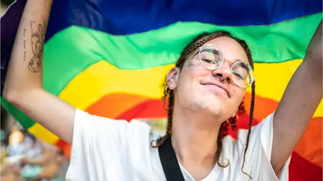 Joven de la generación Z con la bandera del orgullo gay.