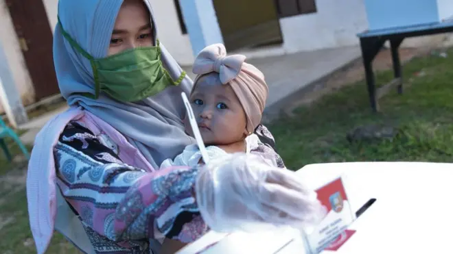 Warga membawa anaknya saat memberikan hak suaranya pada Pilkada Kabupaten Konawe Selatan di TPS 3 Desa Langgea, Kecamatan Ranomeeto, Konawe Selatan, Sulawesi Tenggara, Rabu (9/12/2020)