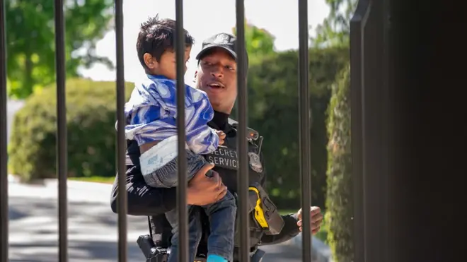 A US Secret Service uniformed division police officer carries a child that snuck through the bars of the White House fence.