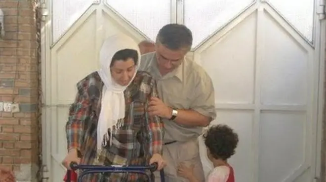 آقای رحمانی در حال کمک به نرگس محمدی که با واکر راه می‌رود