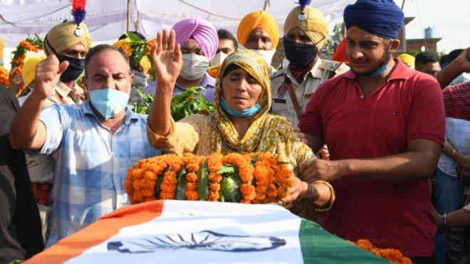 Kashmir Kaur (C) gestures after laying the wreaths of flowers on the coffin of her son and soldier Satnam Singh