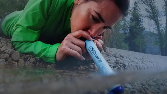 فتاة تشرب من النهر باستخدام أنبوب لايف سترو