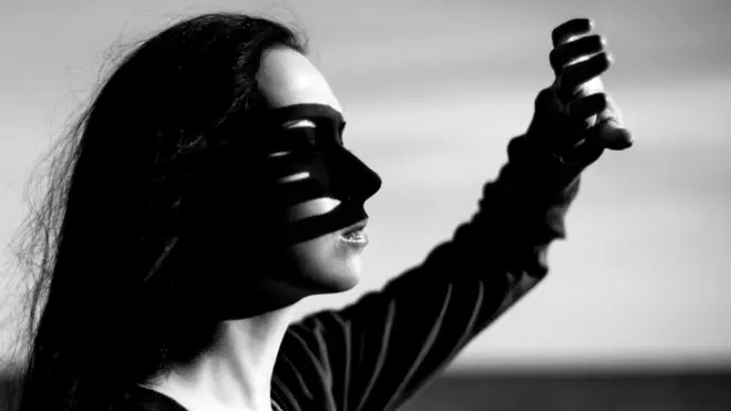 Девушка защищается рукой от солнечного света