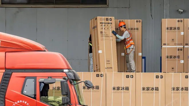 Un trabajador mueve una gran caja que contiene un refrigerador en una bodega en Zhaoqing, provincia de Guangdong, China