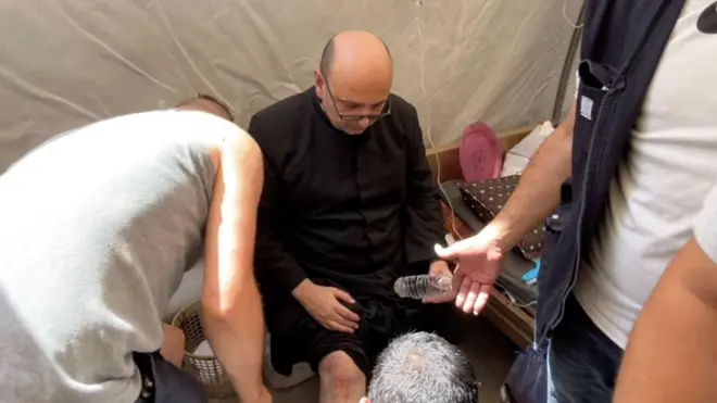 الأب جبرائيل رومانيلي يتلقى الرعاية الطبية، بعد إصابته بجروح طفيفة في ساقه إثر غارة إسرائيلية على الكنيسة