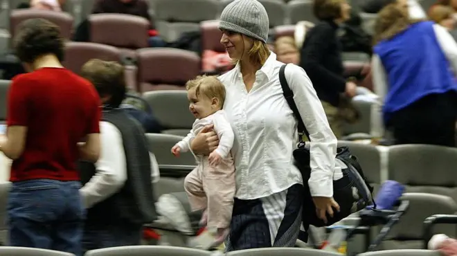 жена у наручју носи бебу, хода између седишта у биоскопу 