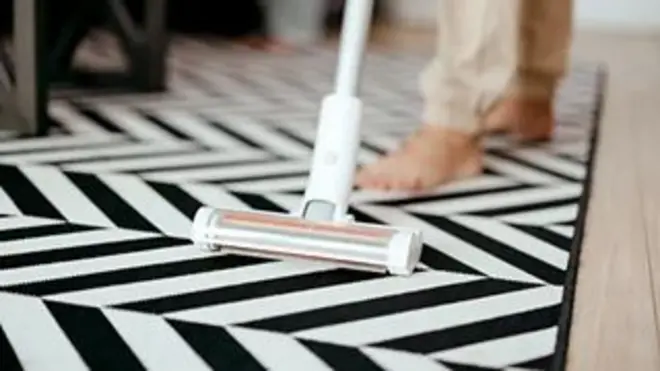 Жінка прибирає у вітальні вдома