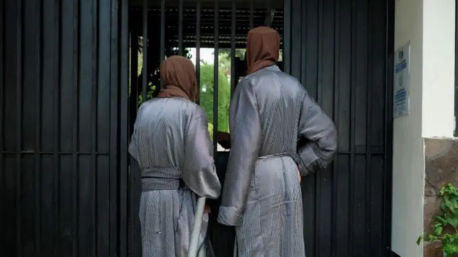 Miembros de la comunidad judía Lev Tahor de espaldas y ataviados con túnicas largas y pañuelos que les tapan completamente la cabeza.