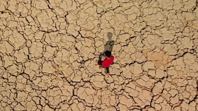 شاب يمشي على تربة متشققة وجافة في منطقة الأهوار في محافظة ميسان جنوب شرق العراق