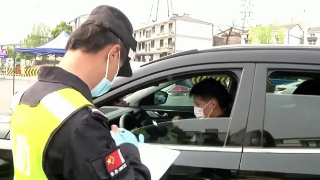 Polisi China mengawasi warga yang keluar masuk.