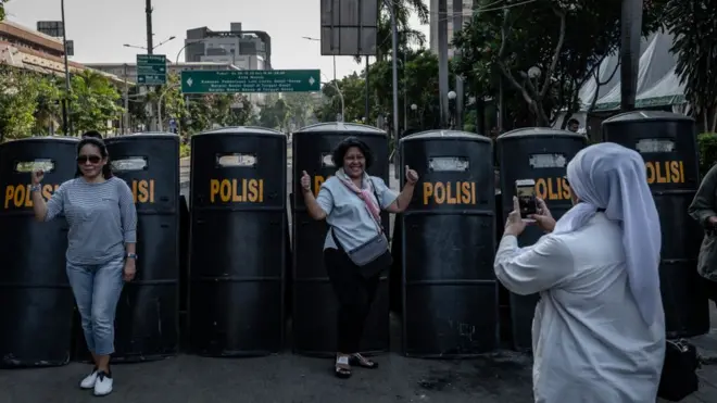 Orang-orang berfoto di depan tameng polisi di depan Bawaslu, 23 Mei 2019.