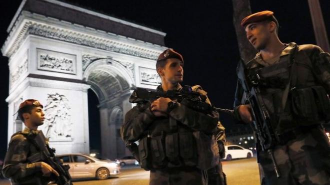 Armed French soldiers stand guard at the Arc de Triomphe on the Champs Elysee Avenue