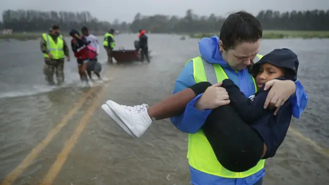 an emergency worker carries a child