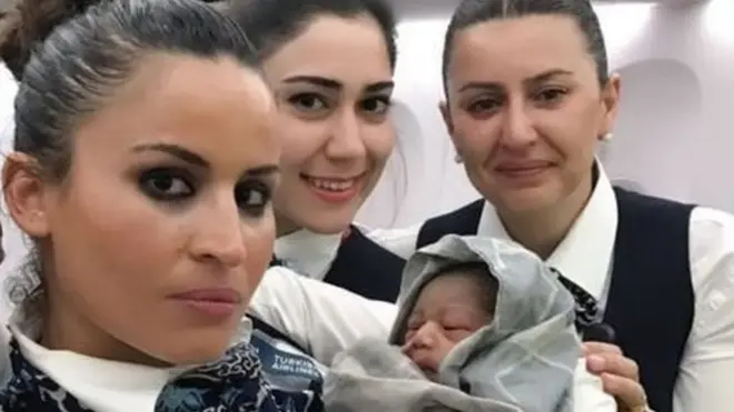 बच्चे के साथ केबिन क्रू की सदस्य.