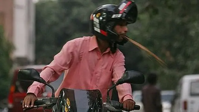 Seorag pengendara motor meludah di jalan di New Delhi.