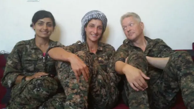 مايكل إنرايت مع اثنتين من مقاتلات وحدات حماية المرأة الكردية (كلاهما قُتلا في معاركهما مع عناصر تنظيم الدولة) في سوريا.